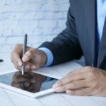 Homem de terno usando caneta digital em um tablet