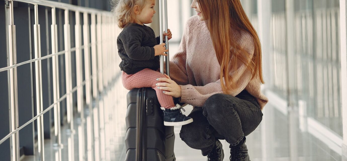 Mulher e menina sentadas com malas no aeroporto