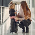 Autorização de viagem para menor de idade: quando precisa e como fazer Mulher e menina sentadas com malas no aeroporto