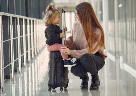 Mulher e menina sentadas com malas no aeroporto