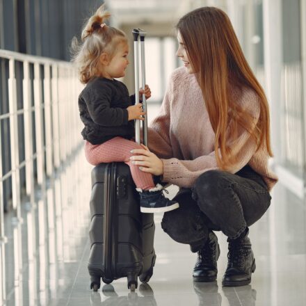 Mulher e menina sentadas com malas no aeroporto