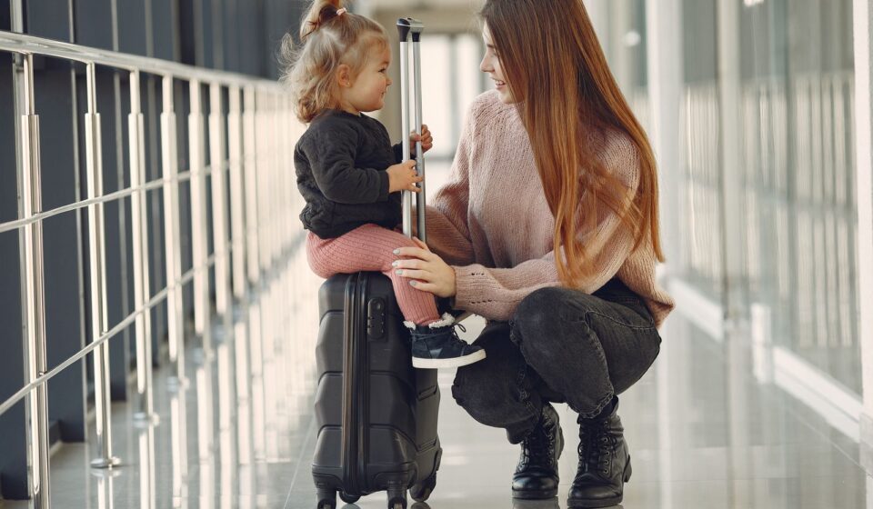 Mulher e menina sentadas com malas no aeroporto