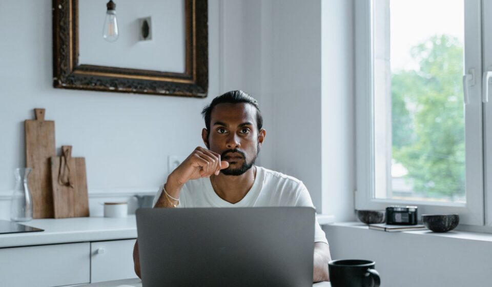 Homem trabalhando no laptop em uma mesa clara