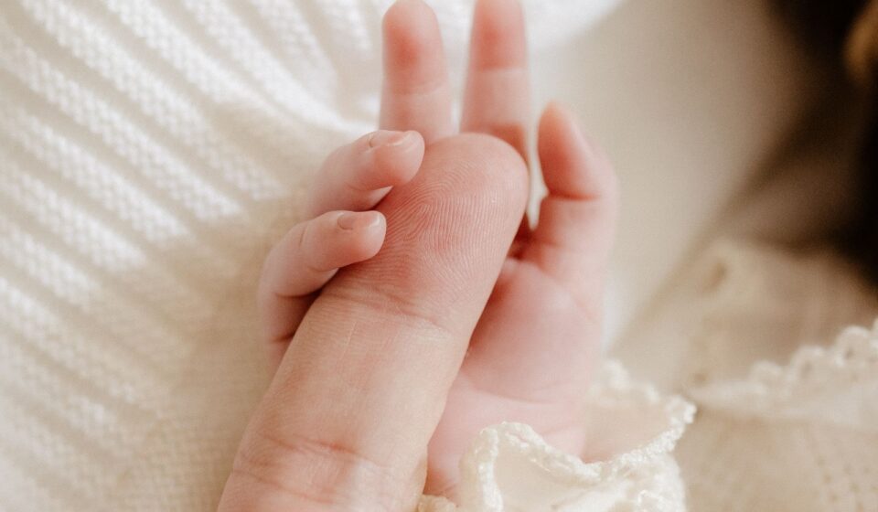 Mão de bebê segurando o dedo de um dos pais