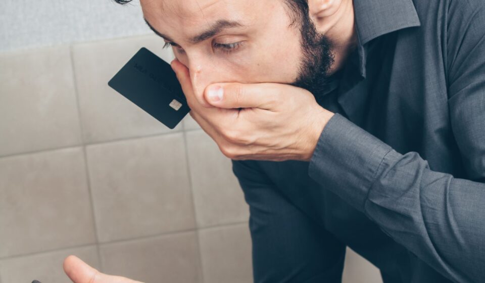 Homem surpreso olhando o celular e segurando um cartão