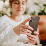 Não votou no 2º turno? Como justificar a ausência pelo e-Título Mulher sentada no sofá usando o celular