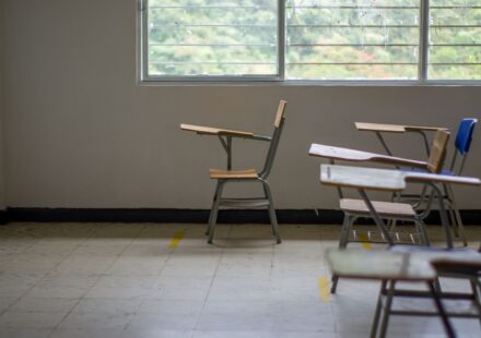 Sala de aula vazia com carteiras perto de uma janela