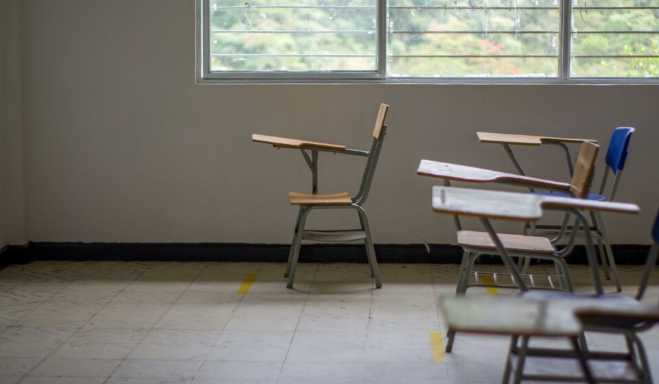 Sala de aula vazia com carteiras perto de uma janela
