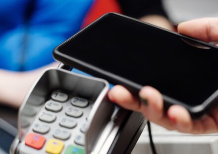 Mão fazendo pagamento por aproximação com o celular