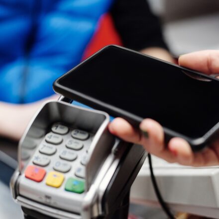 Mão fazendo pagamento por aproximação com o celular