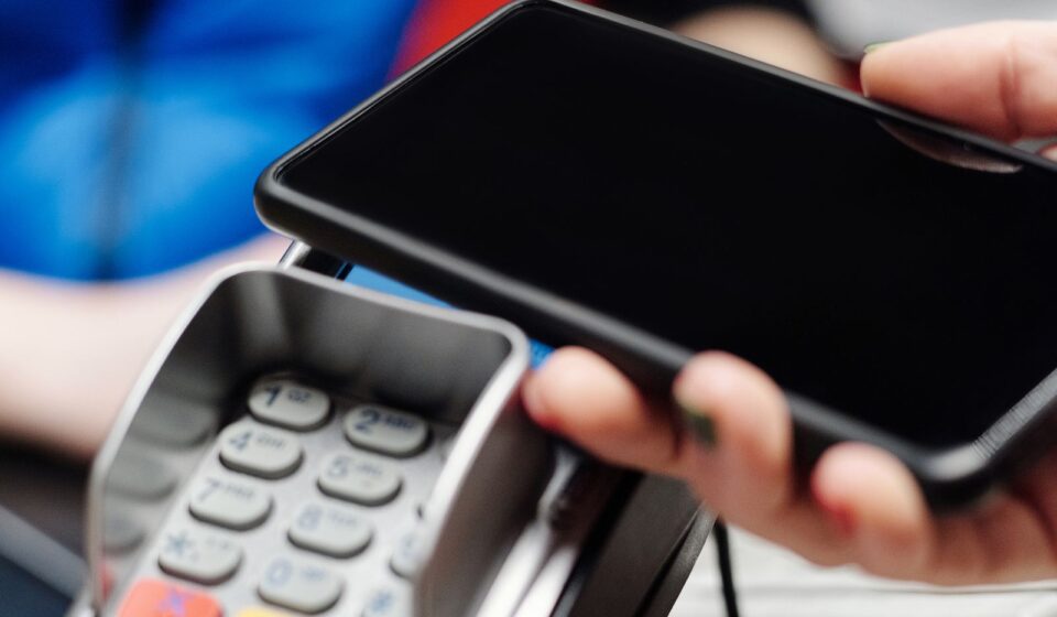 Mão fazendo pagamento por aproximação com o celular