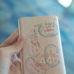 Mão segurando um passaporte aberto com carimbos