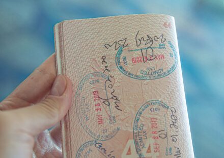 Mão segurando um passaporte aberto com carimbos