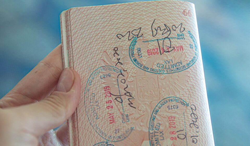 Mão segurando um passaporte aberto com carimbos