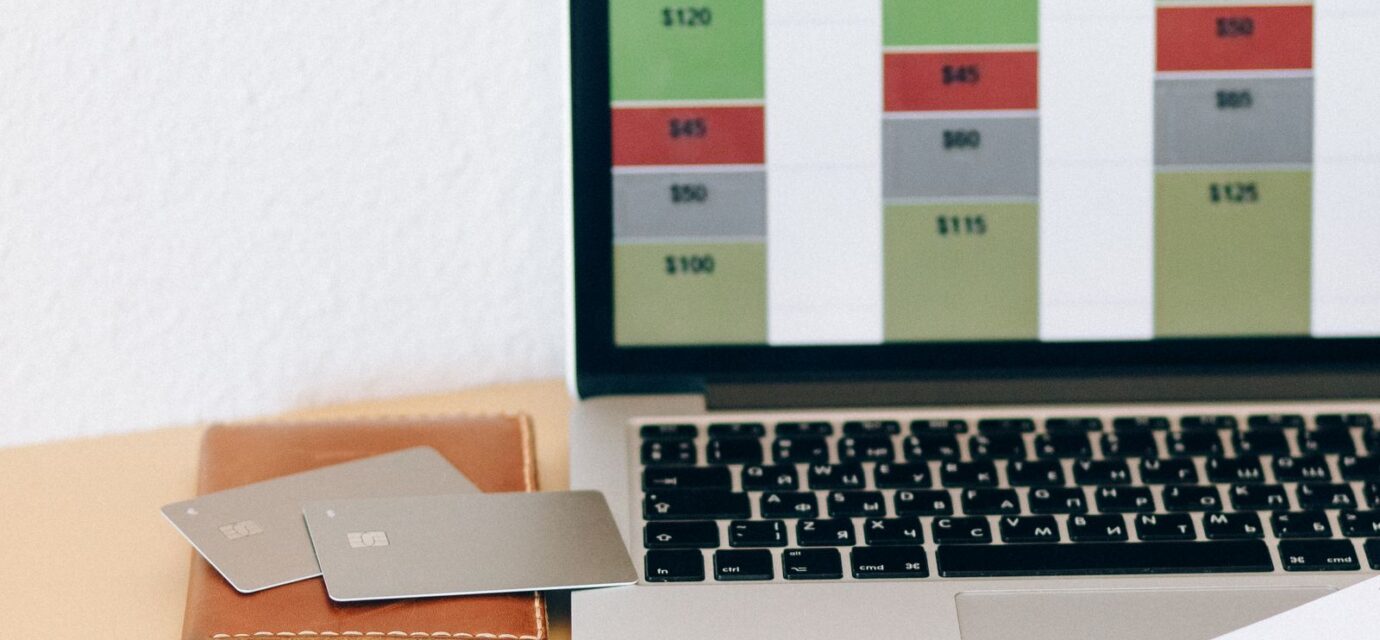 Laptop com gráfico financeiro ao lado de documentos e cartões