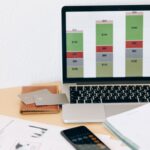 Laptop com gráfico financeiro ao lado de documentos e cartões