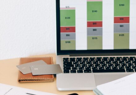Laptop com gráfico financeiro ao lado de documentos e cartões