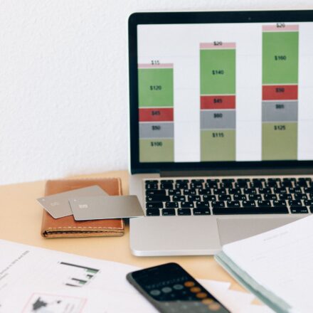 Laptop com gráfico financeiro ao lado de documentos e cartões