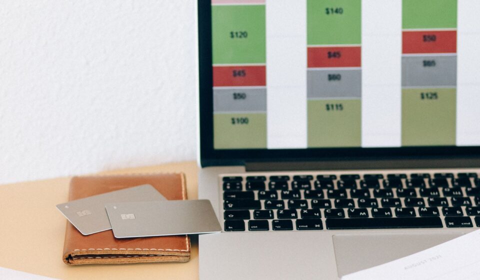 Laptop com gráfico financeiro ao lado de documentos e cartões